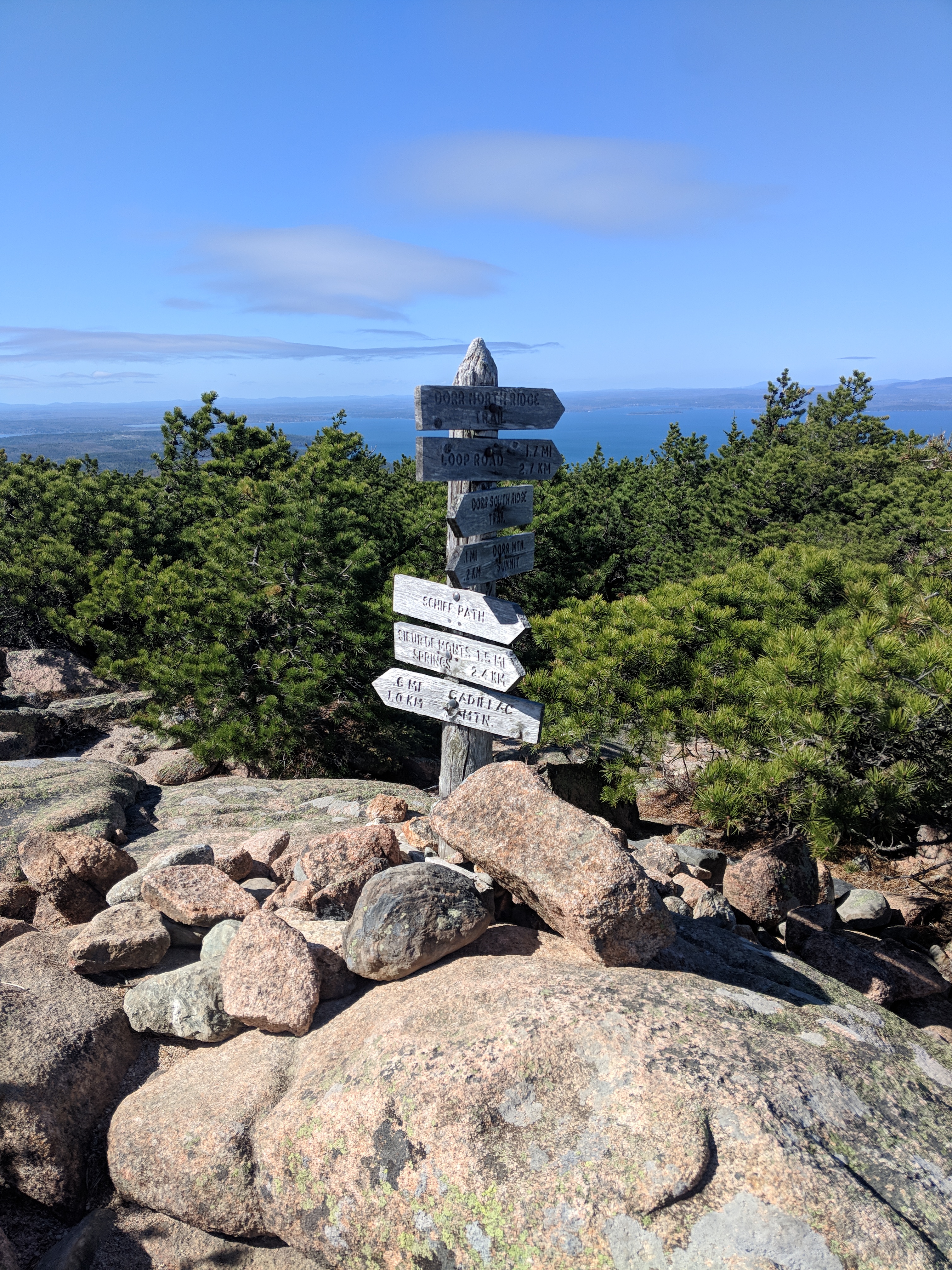 Sign atop a mountain in Acadia showing the direction for 7 different trails